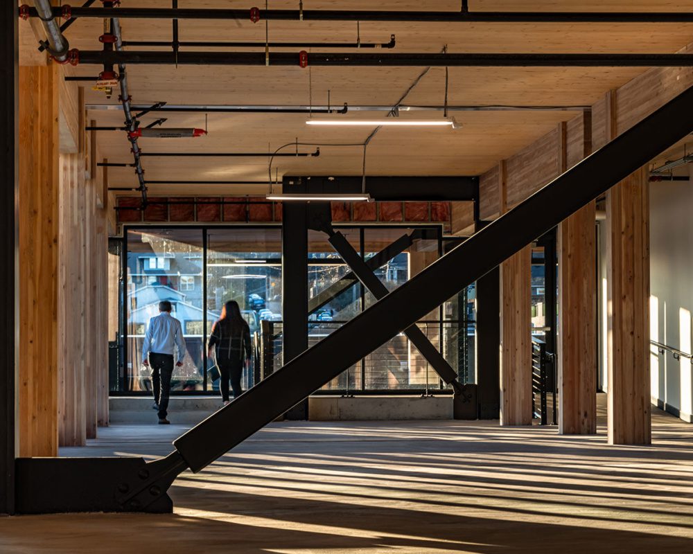 Photo of the interior of northlake commons with the expressed steel beams showing in contrast with the mass timber with the sun beaming through