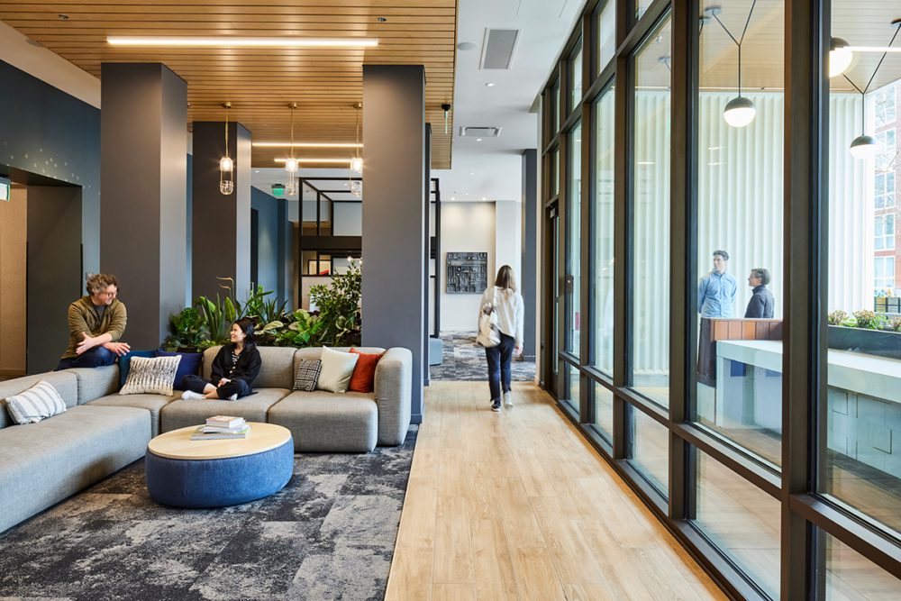 Photo of the Accolade interiors with a student walking down the hall and other students talking