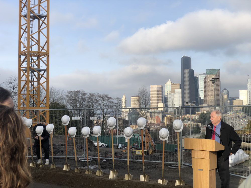 Photo of Frank Chopp speaking at the North Lot ground breaking ceremony. Seattle is in the background with shovel and hard hats in the foreground.