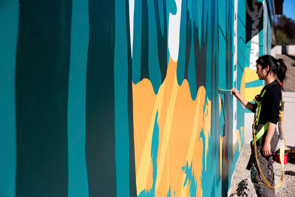 Photo of Artist Tori Shao painting the mural at Northlake Commons