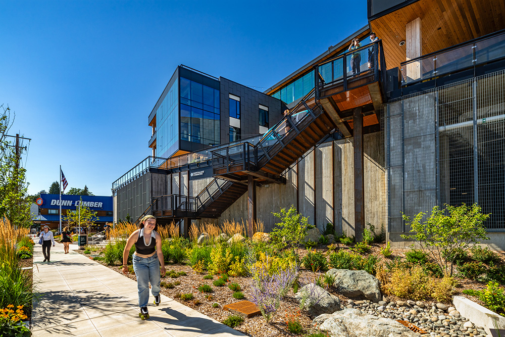 sunny photo of a girl roller skating on a side walk outside northlake commons mass timber building