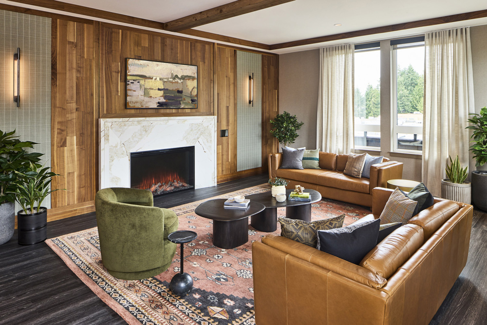 photo of the interior with warm wood tones, a fireplace, brown leather couches, and a bright window