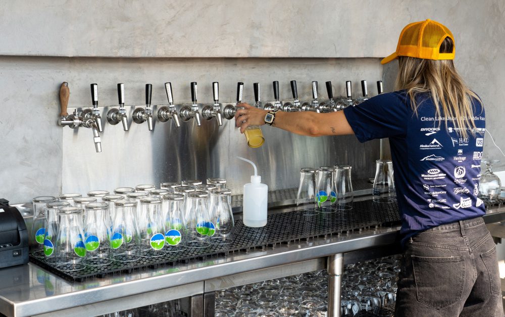 photo of the gasworks brewing bartender pouring beer from taps into a clean lake union branded pint glass