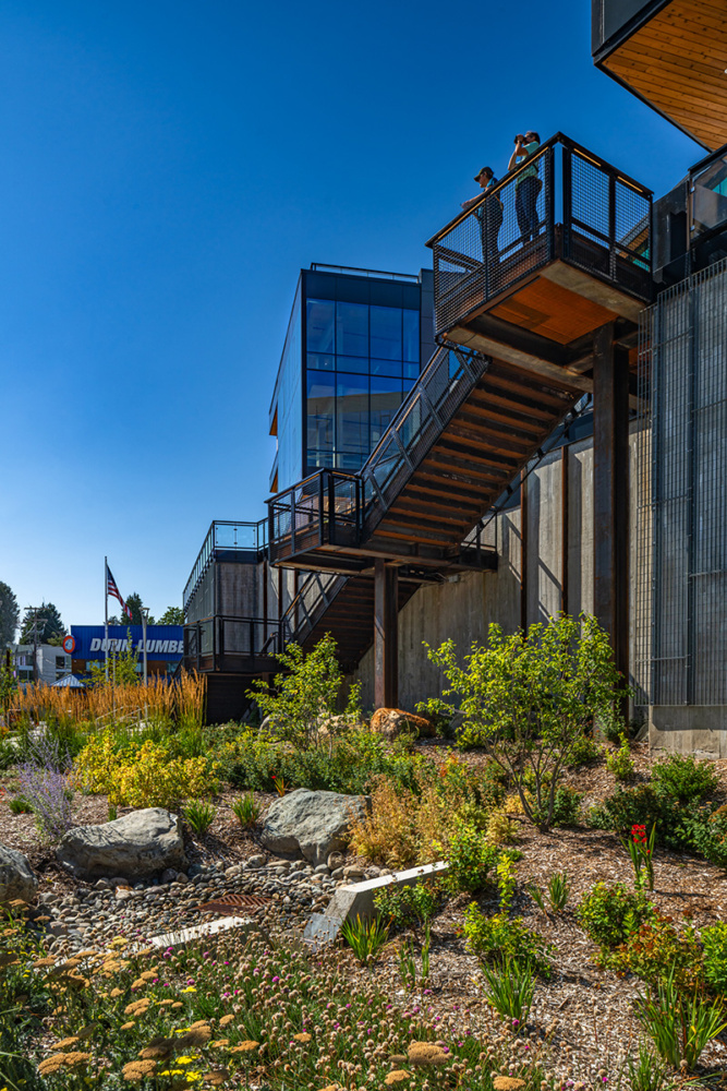 photo outside at northlake commons looking at the bioswale on a sunny day. two people stand at the staircase overlooking the swale towards lake union