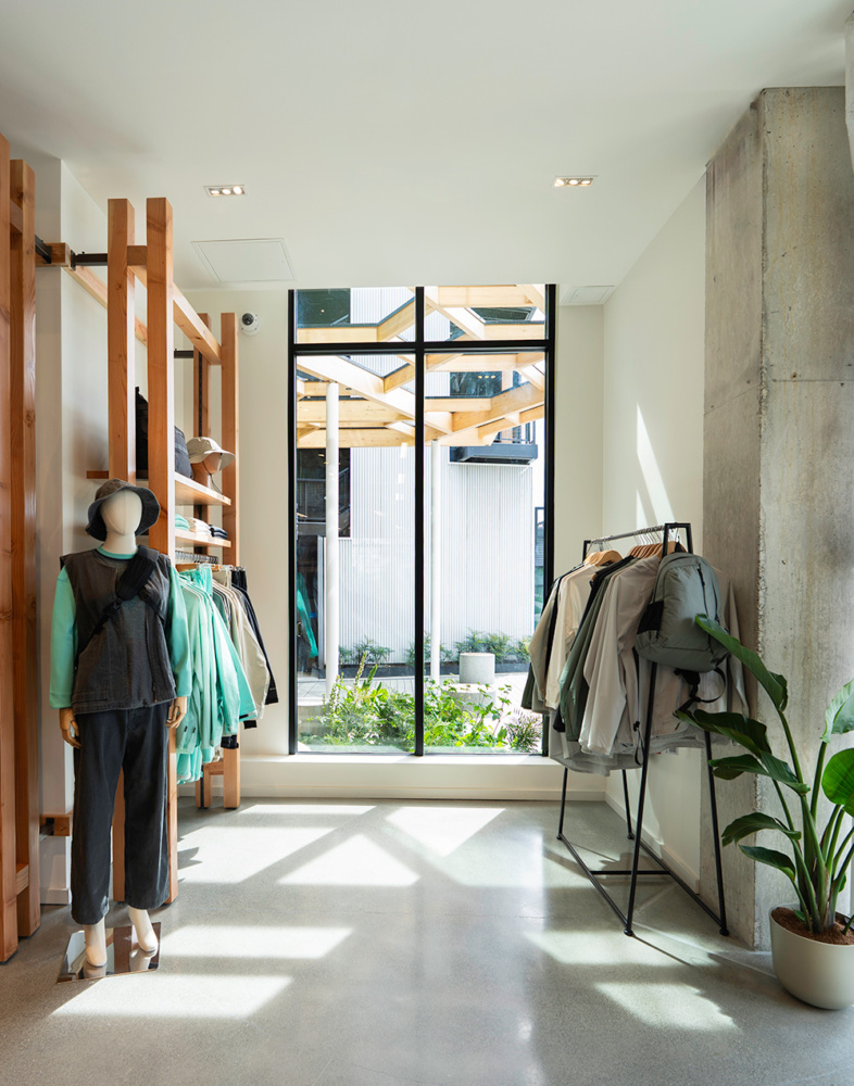 photo of the interior of snow peak seattle looking out a window with sunshine coming through, a wood pergola stands outside