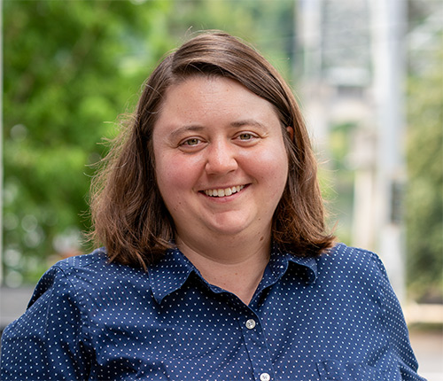 Portrait of Caitlyn Salters taken outdoors with green foliage in the background
