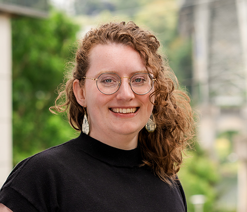 Portrait of Melia Barnes taken outdoors with green foliage in the background