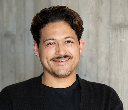 Portrait of Noah Scanlan with a textured concrete wall in the background