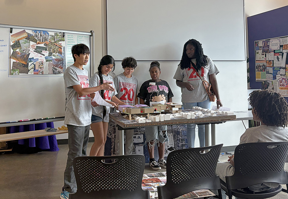 photo of students presenting their work standing in front of the room