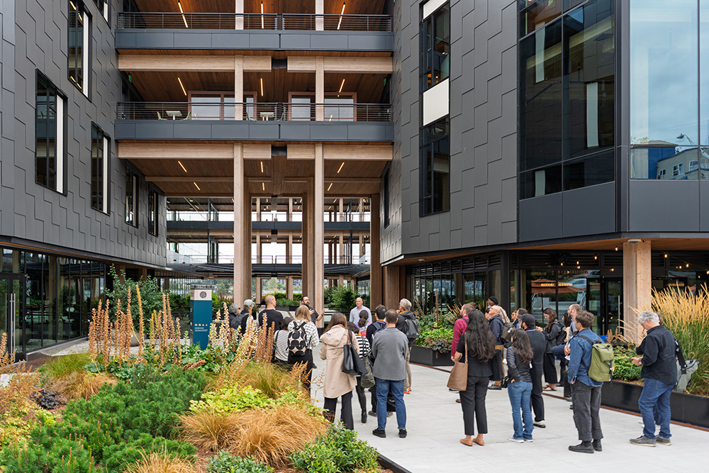 photo of a group of professors gathered outside a mass timber building with green landscaping in the forefront